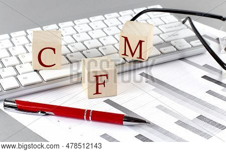 Cfm Written On Wooden Cube On The Keyboard With Chart On Grey Background