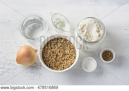 Ingredients: Green Lentils, Onions, Flour, Water, Vegetable Oil, Salt And Pepper On A Light Blue Bac