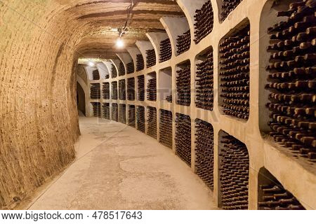 Old Bottles Of Wine Stacked In Rows In The Cellars Of A Winery