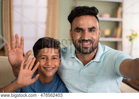 Happy Smiling Indian Father With Son Talking Video Call By Holding Camera At Home - Concept Of Long 