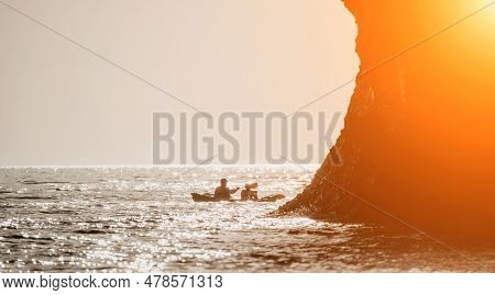 Happy Couple Kayaks In An Inflatable Kayak On The Sea At Sunset. Couple Kanoeing In The Sea Near The