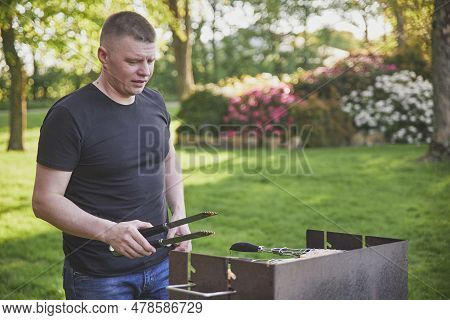 Skjern, Denmark, May 21, 2023: Man Roasting Meat On Coals