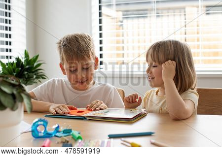 Brother And Sister Together Amicably Read An Educational Book. The Concept Of A Happy Childhood.