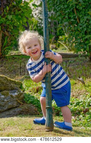 Happy Young Boy With Playful Smile In Garden During Summer Sunshine