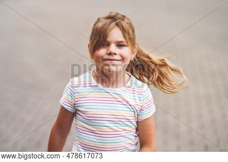 Happy Little Girl Runs On The Street In The City, Outdoors. Funny Preschool Child Enjoys Running, Wa