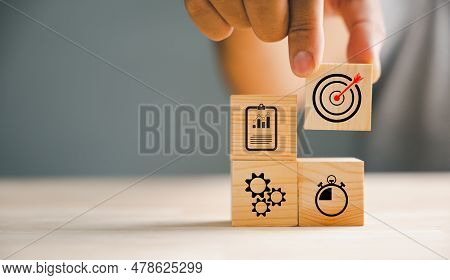 Businessmans Hand Meticulously Arranging Wood Blocks, Representing A Business Strategy And Action Pl