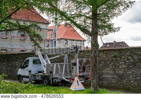 Car Lift Stands On The Sidewalk Against The Background Of An Antique Stone Wall. Spring Tree Pruning