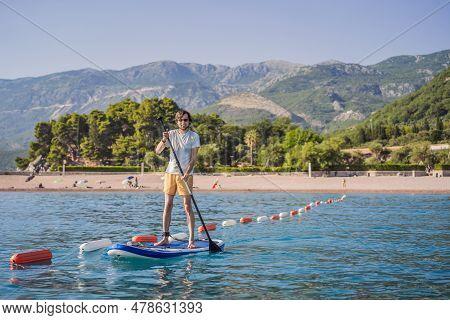 Young Men Having Fun Stand Up Paddling In Blue Water Sea Near St Stefan Island In Montenegro. Sup