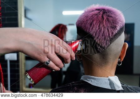 The Hairdresser Shaves The Temple Of A Female Client. Rear View Of A Woman With Short Pink Hair In A