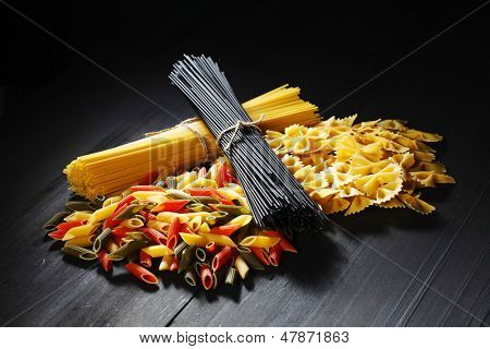 Olika typer och former av italiensk pasta på svart bord
