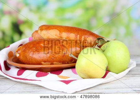 Empanadillas al horno frescos con mermelada de frutas, en la mesa de madera, sobre fondo brillante