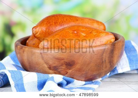 Empanadillas al horno frescos, en un recipiente de madera, en la mesa de madera, sobre fondo brillante
