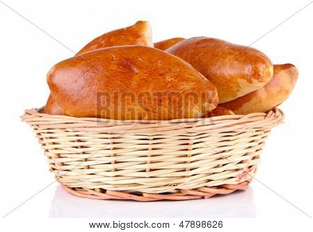 Empanadillas al horno frescos en cesta de mimbre, aislados en blanco