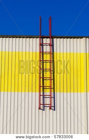 Red ladder on a white-yellow wall.