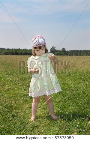 Little Barefoot Girl Plays With Camomile At Green Meadow At Summer Sunny Day