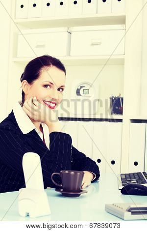 Young nbeautiful business woman is having break with cup of coffee or tea.