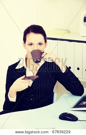 Young nbeautiful business woman is having break with cup of coffee or tea.