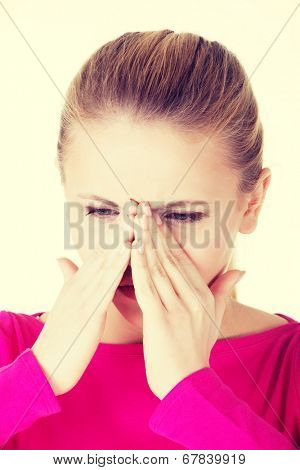 Young caucassian woman is having sinus pressure, touching her nose. Isolated on white.
