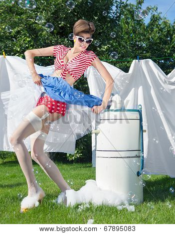 Skirt caught by wringer, pin up style photo of woman with vintage washing machine doing laundry outdoor