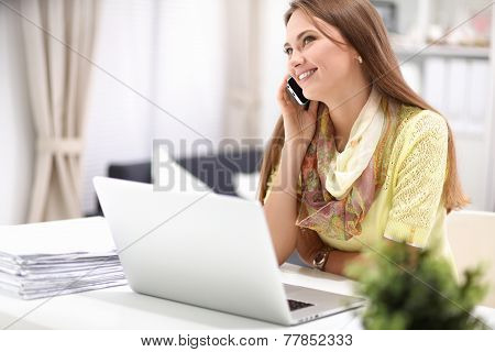 Woman using mobile phone and laptop at home