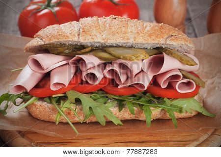Submarine sandwich with baloney, pickles, tomato and rocket salad