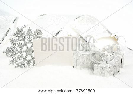 Silver Christmas Decoration On Snow With Wishes Card