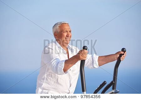 healthy senior man working out on gym treadmill machine at modern home terace with ocean view