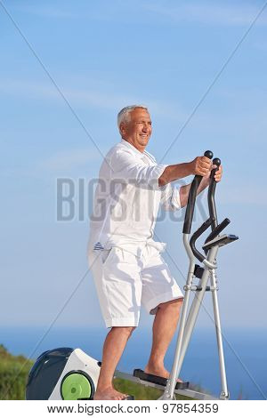 healthy senior man working out on gym treadmill machine at modern home terace with ocean view