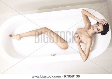 Young Woman Lying On The Side In The Bathtub And Relax Covering Her Breasts With Her Hand.