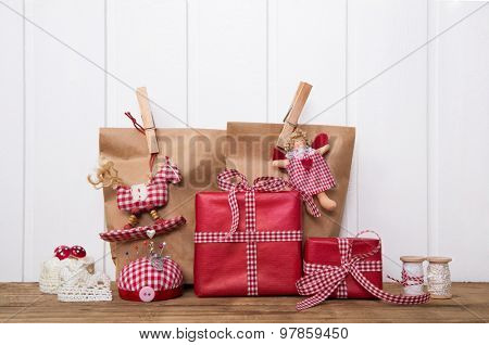 Christmas presents wrapped in paper bags with red white checked ribbon, angel, rocking horse and sewing supplies.