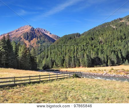 The picturesque mountain valley. Rapid stream, dense coniferous forest and easy farm fence. National Park Krimml 