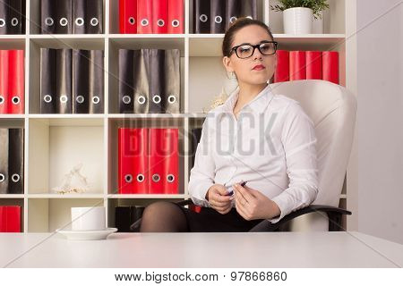 Business woman sitting near the desk with cup of coffee and thinking