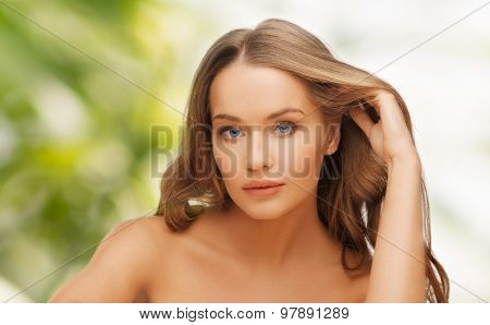 people, beauty and hair care concept - beautiful woman face with long blond hair over green natural background