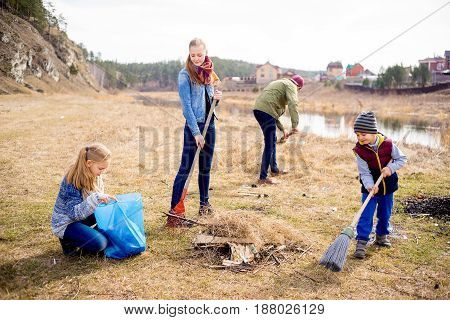 A happy family of four is cleaning outside