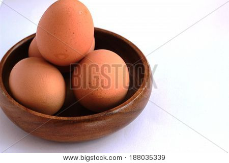 Boiled eggs that are not peeled and peeled in a brown container on a white background.