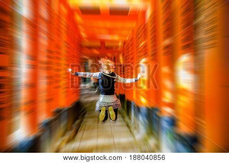 Buddhist temple defocused background. Adventure, exploration, travel concept. Happy tourist woman jumping under red torii gates with blurred motion effect. Fushimi Inari shrine, Kyoto, Japan.