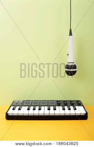 Musical instrument - MIDI keyboard and vokal microphone for a karaoke hangs down on top on a flavovirent background.