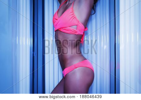 Slim Woman Standing In Solarium Getting Sun Tan
