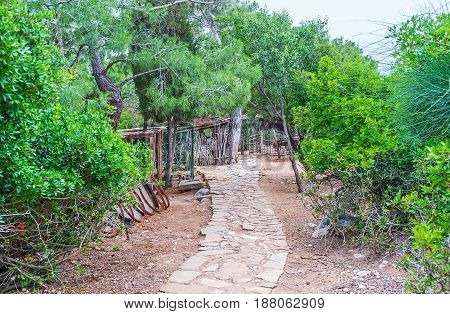 The narrow winding stone path among the greenery of Yoruk park located on the hill in Kemer Turkey.