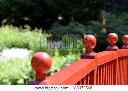 Light brown bridge wooden fence with wooden balls and the bockeh green path background