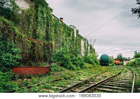 Old industrial railroad station platform, overgrowth with green grass, post apocalypse urbex concept