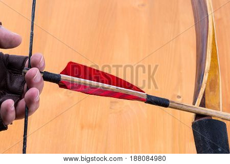 Archer Wearing Open Fingers Leather Gloves Drawing A Traditional English Longbow With A Red Feather