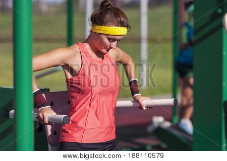 Portrait of Concentrated Caucasian Female Athlete in Professional Training Outfit Having Outdoor Workout Exercises on Weights.Horizontal Shot