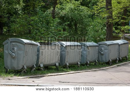 Row of large green wheelie bins for rubbish recycling and garde