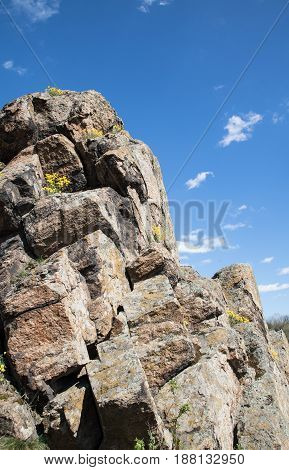 Close-up View Cascade Of Stones On The Rock, Blue Sky On The Background, Yellow Flowers Between Rock