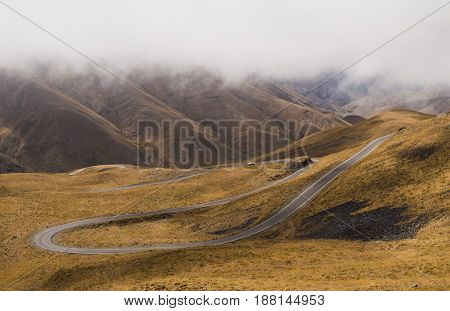 a road between mountains with white cloud . winding roads .