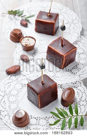 Chocolate souffle candy dessert with chocolate praline and cocoa beans on wooden background close up. Top view.