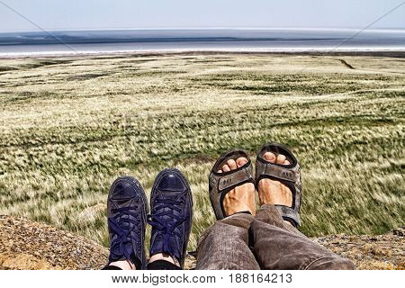 Legs of traveler family sitting on a high mountain