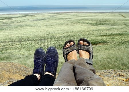 Legs of traveler family sitting on a high mountain