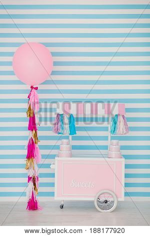 Children's zone with sweets: lollipops, ice cream, macarons, balloon and candy bar. Children room with blue stripe background.